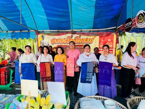 คณะจากสำนักงานพัฒนาชุมชนจังหวัดนครราชสีมา ถ่ายภาพร่วมกันพร้อมถือผ้าลายจักราช